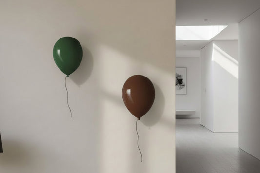 Two balloon sculptures, one green and one brown, attached to a white wall with a room in the background.